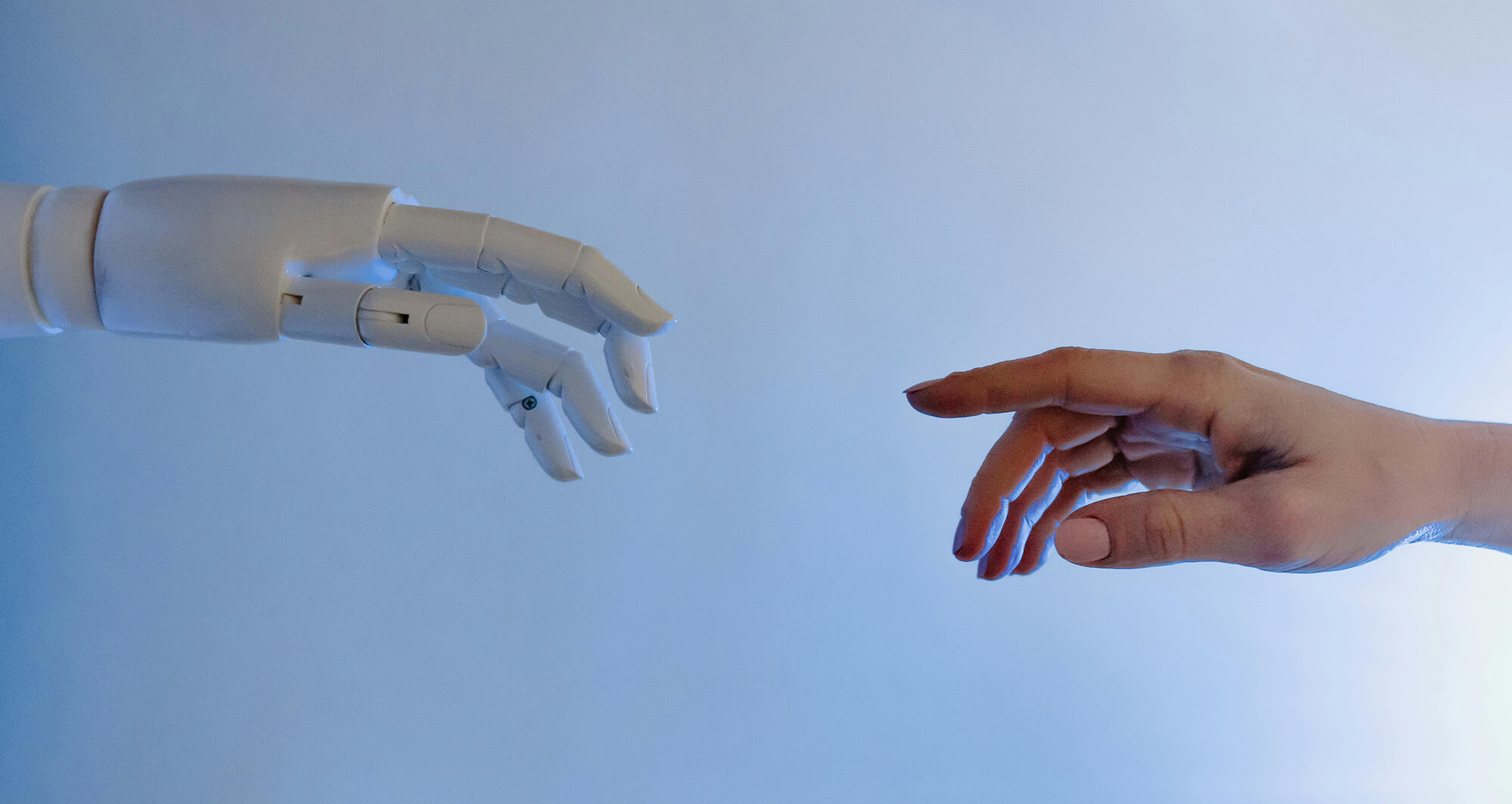 Human hand reaching toward robotic hand, symbolizing human-AI collaboration in technology.