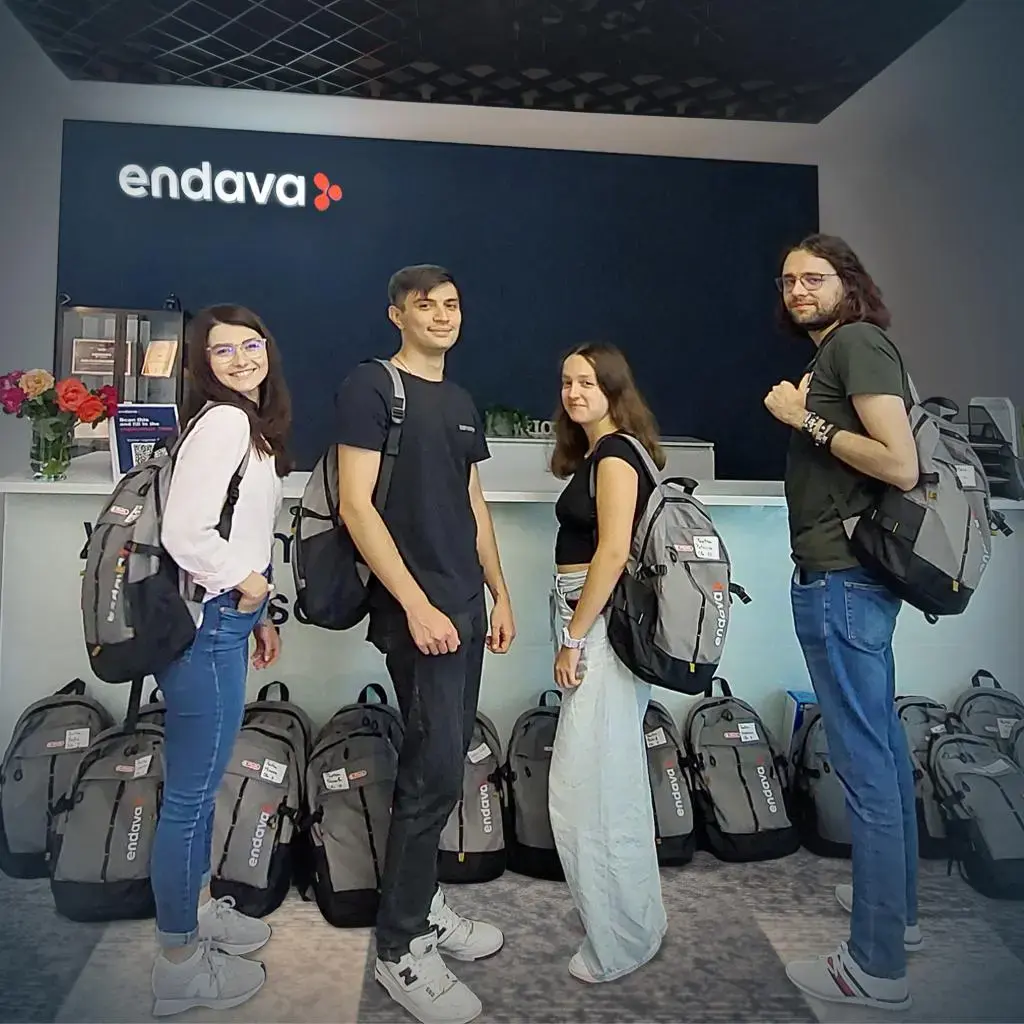 Group of young professionals with Endava backpacks standing in front of company reception desk.