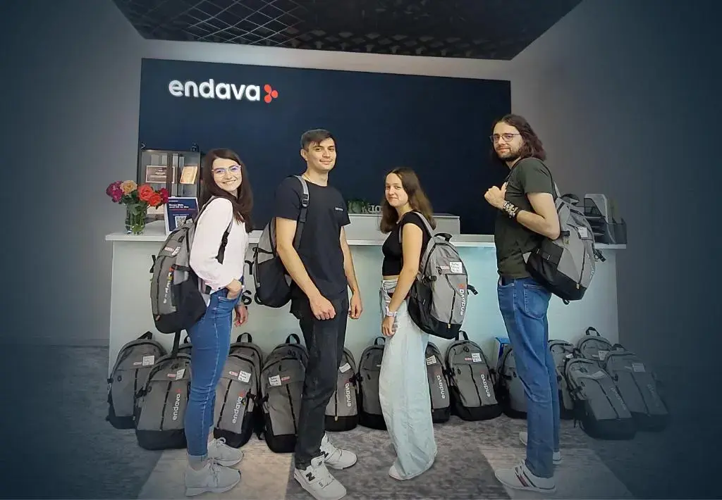 Group of young professionals with Endava backpacks standing in front of company reception desk.