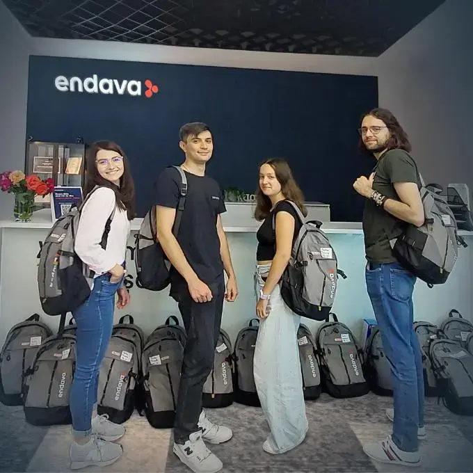 Group of young professionals with Endava backpacks standing in front of company reception desk.