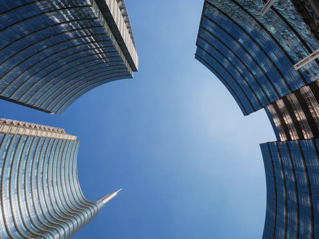 Upward view of modern glass skyscrapers against a clear blue sky in a financial district.