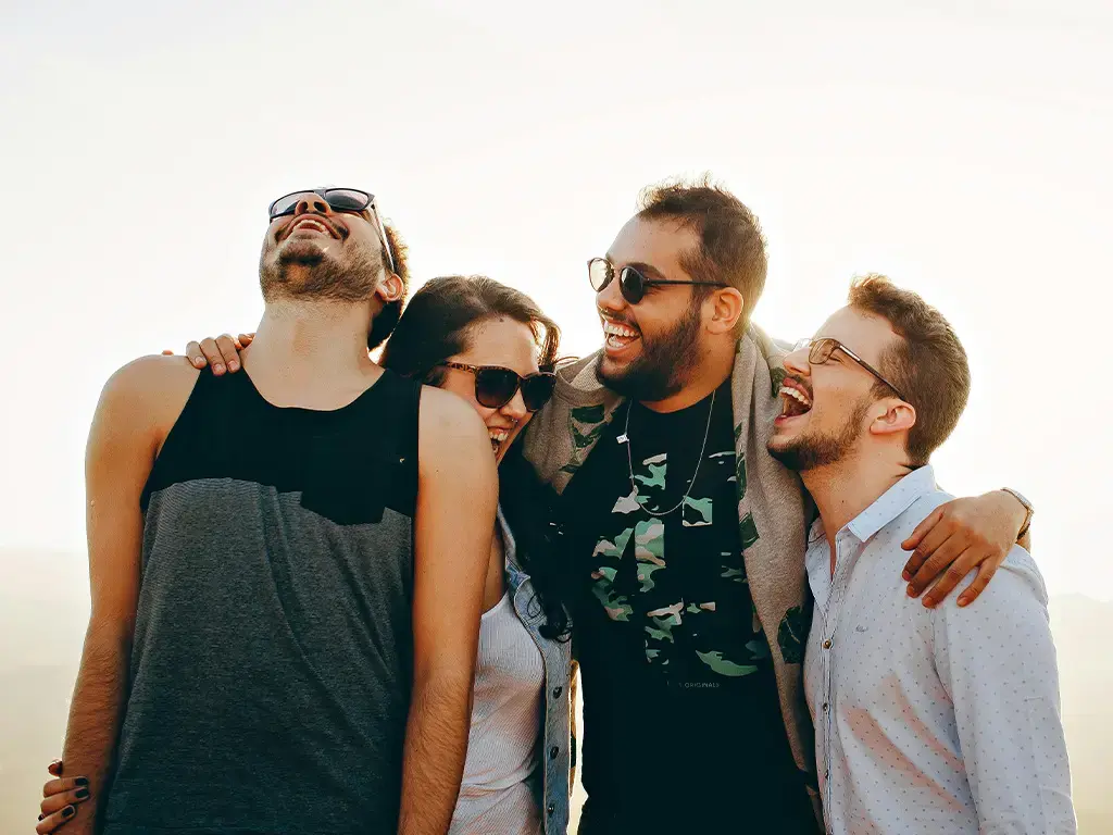 Group of friends outdoors smiling and laughing, symbolizing strong team connections.