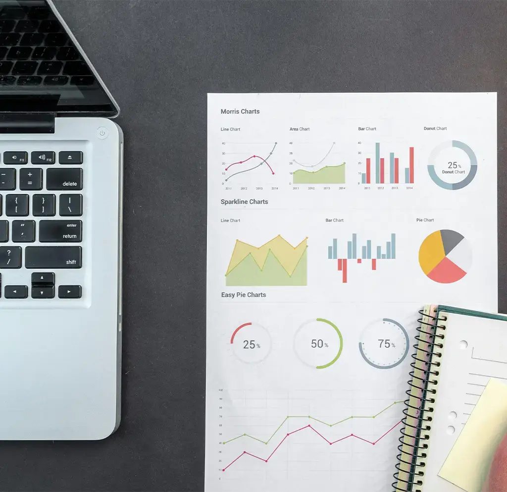 paper charts and notebook next to laptop