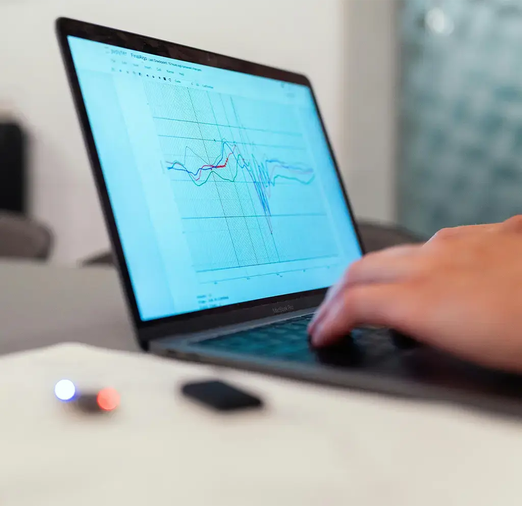 person working on laptop displaying chart with multiple graphing lines