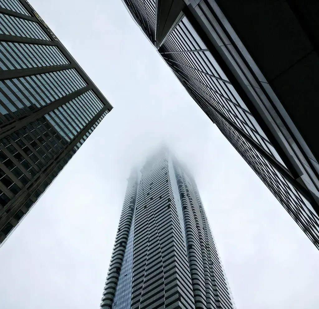 Skyscrapers rise into foggy sky, symbolising growth and innovation in global business infrastructure.