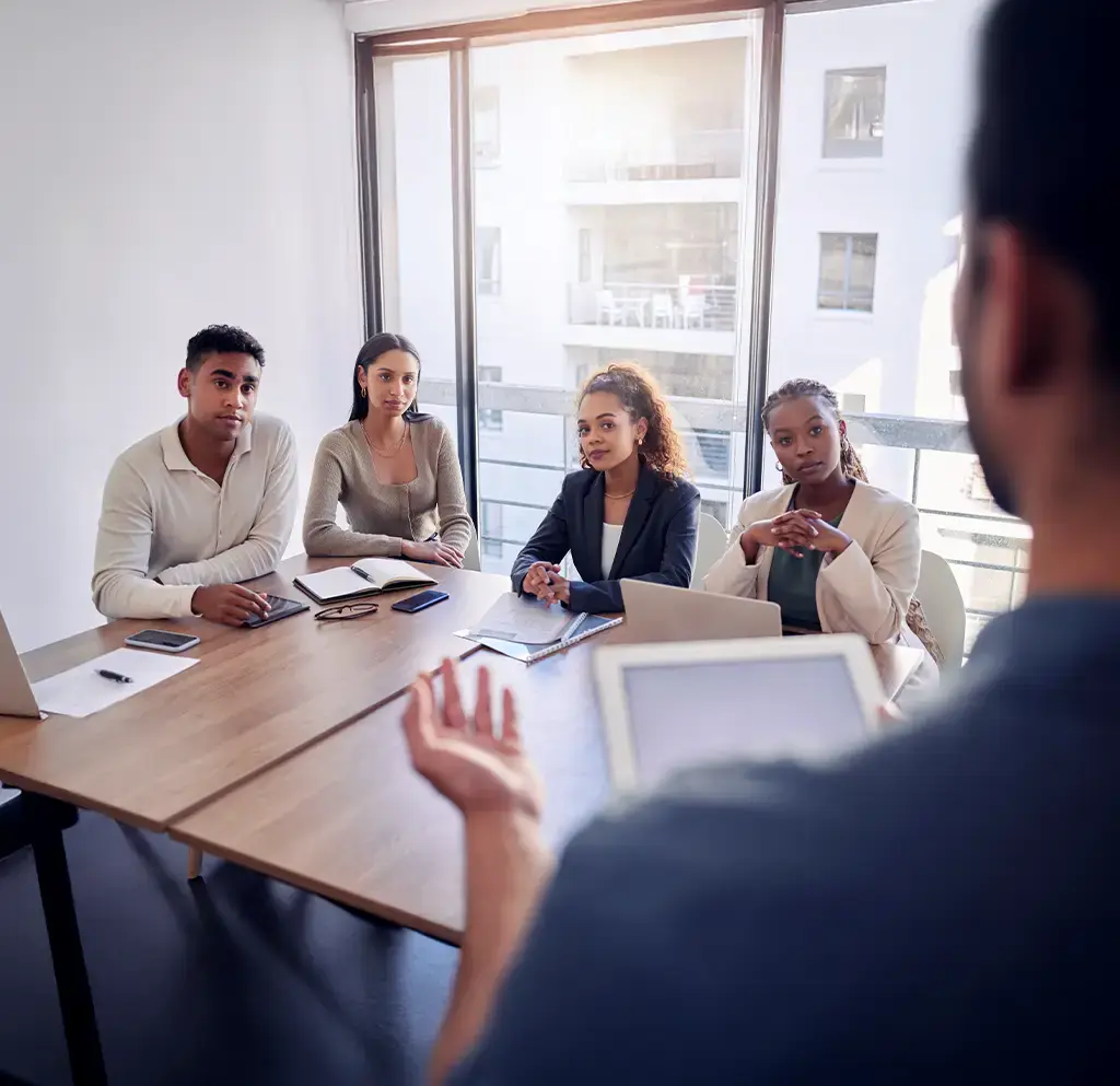 Business team listening to a presentation in a modern office meeting room with natural light.