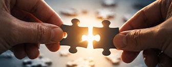 Hands joining puzzle pieces, representing connected thinking and collaborative digital transformation
