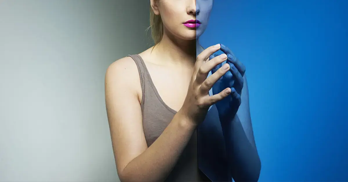 Person standing behind a reflective blue panel, symbolizing digital transformation and dual perspectives in technology.