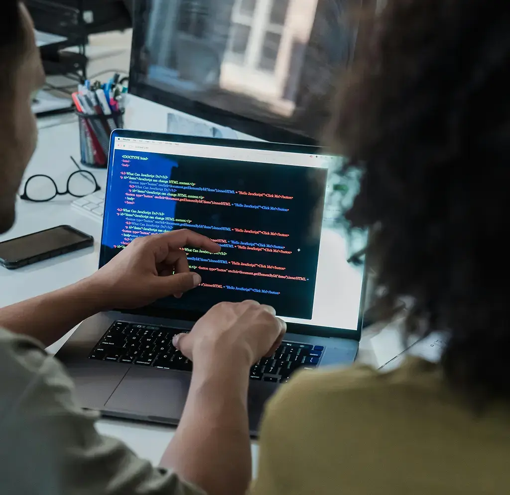 Developers reviewing code on laptop screen in modern workspace