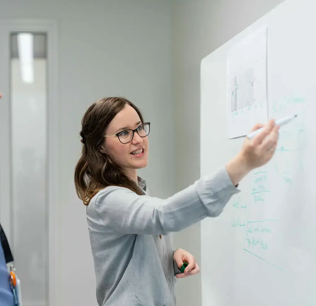 Professional presenting a strategy diagram on a whiteboard during a planning session