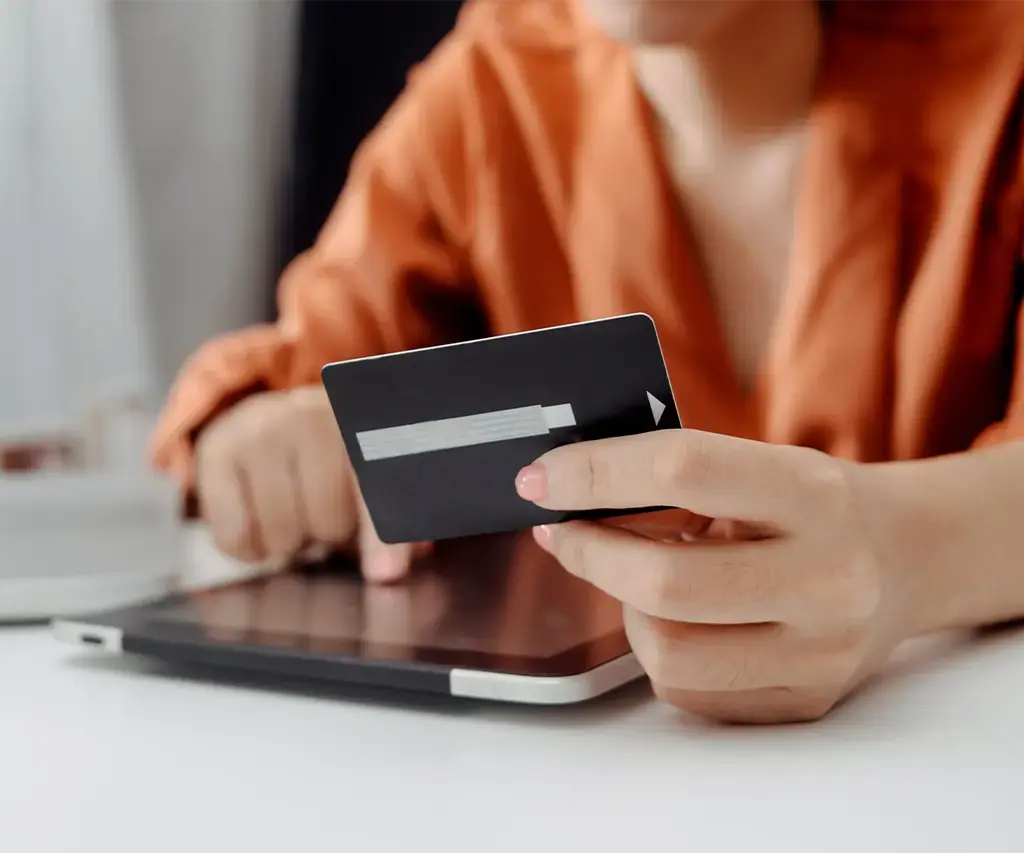 business person hold their credit card in hand while using tablet device