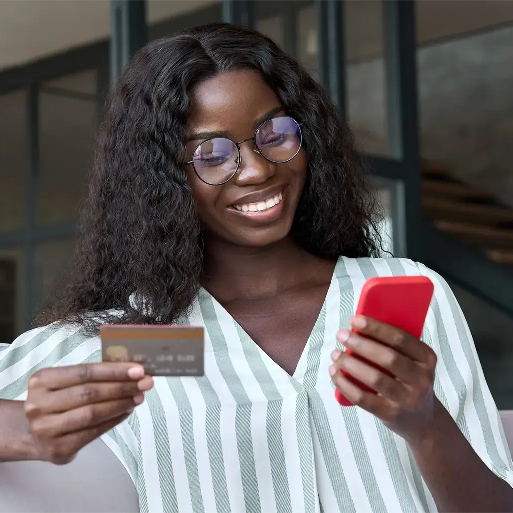 person holding up a credit card while looking at their phone