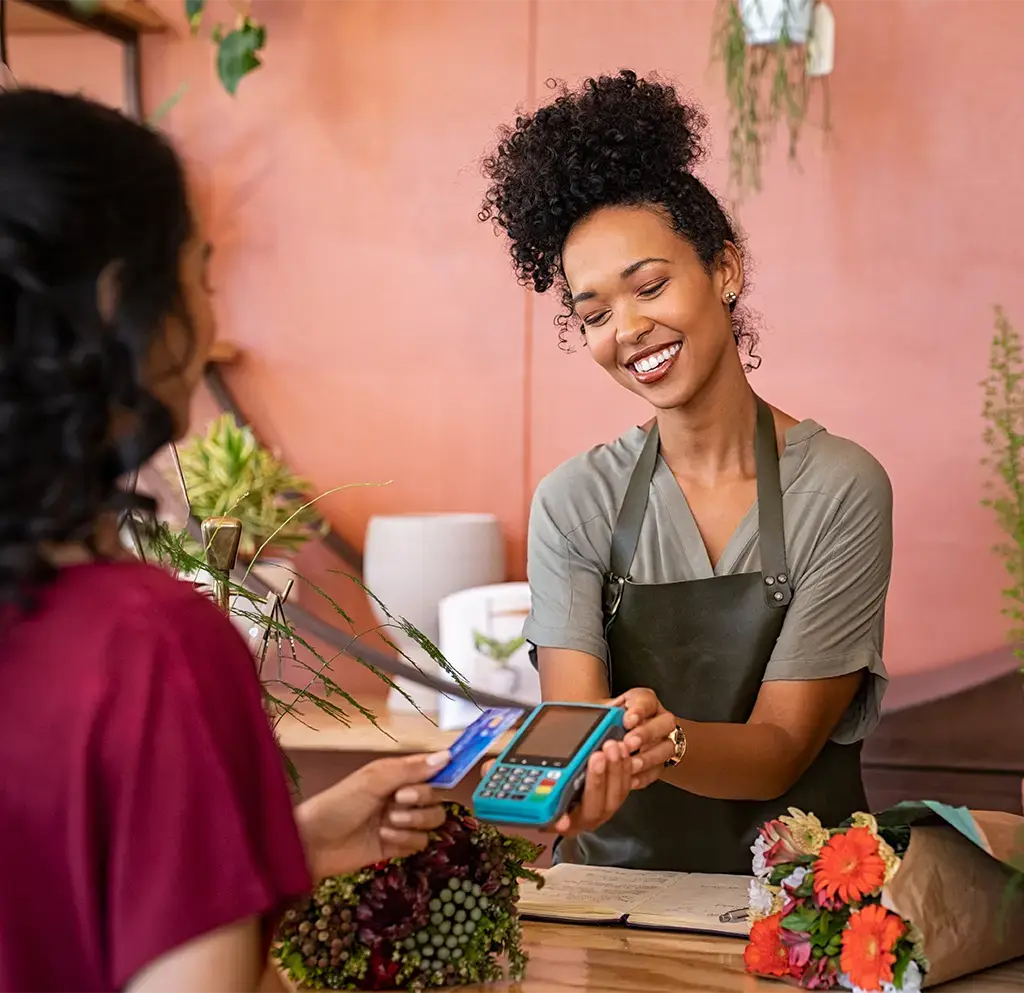 Florist processing a contactless card payment at a flower shop counter.