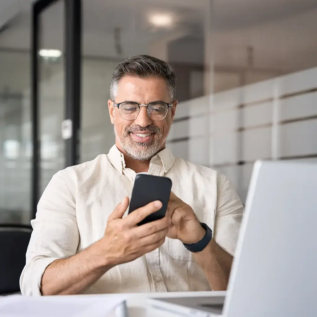 Business professional in a modern office using a smartphone, representing Endava’s partnership with GoCardless