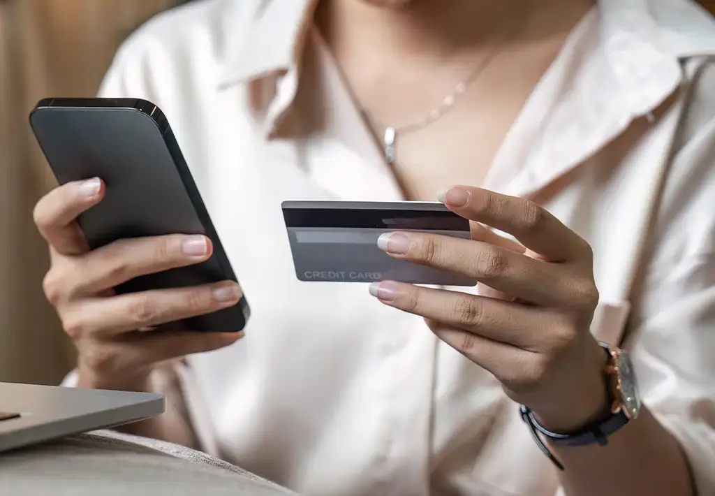A woman exploring a loyalty programme on her phone holding a card