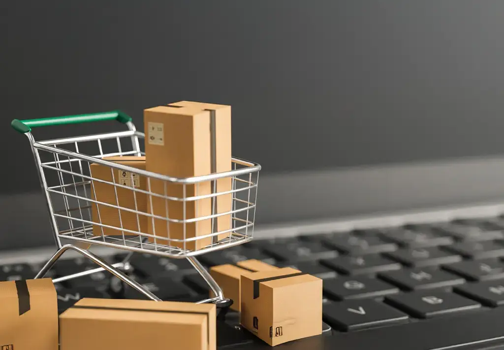 Mini shopping cart with parcels on a laptop keyboard, symbolizing digital commerce and online fulfillment.