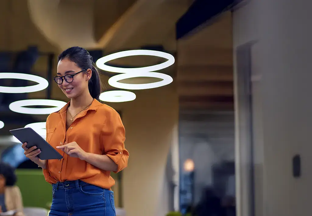 Professional using a tablet to review retail tech insights in a modern collaborative workspace.
