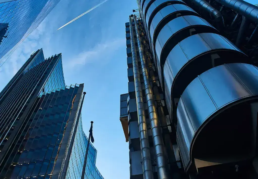 Modern insurance district skyscrapers with reflective glass and steel architecture against blue sky.
