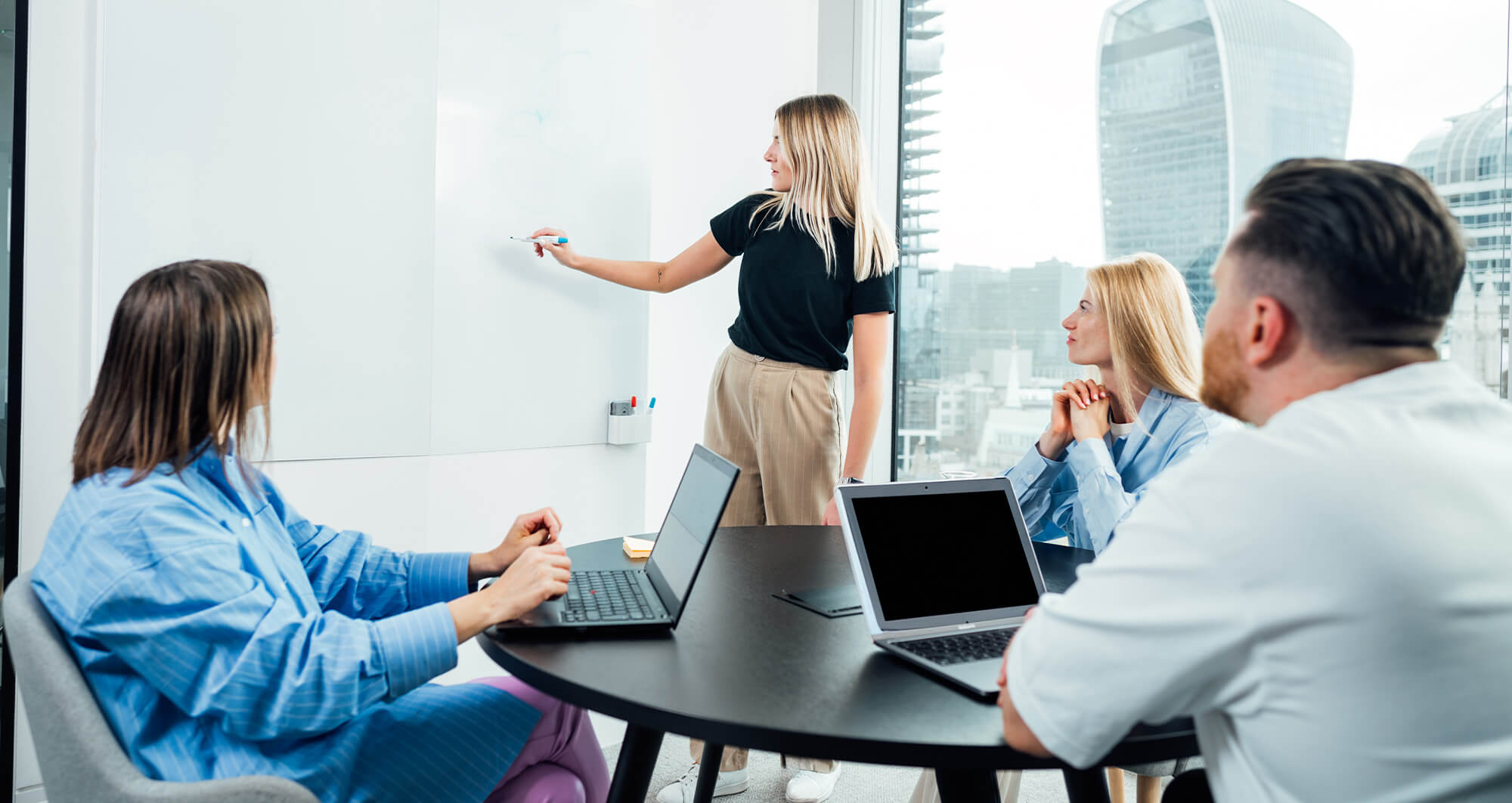 Team collaborating during a strategy session with laptops and whiteboard planning in a modern office.