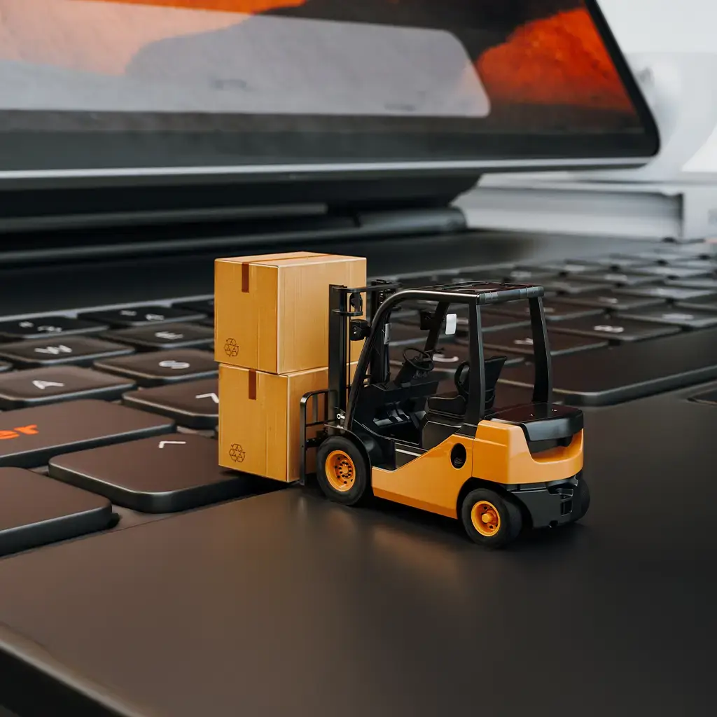 Forklift moving boxes on laptop keyboard, illustrating smart logistics and supply chain digitization.