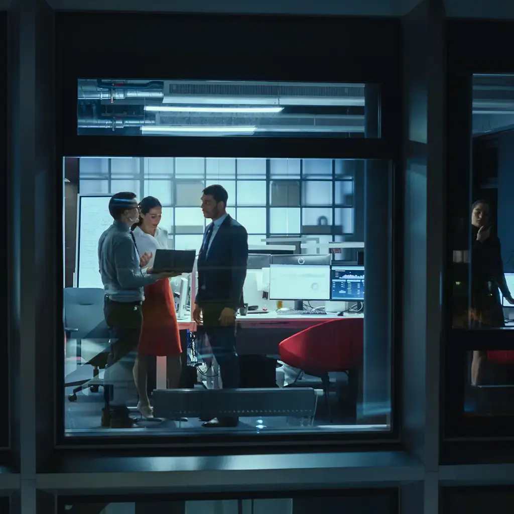 Teams collaborating in a modern office at night, focused on digital project development.