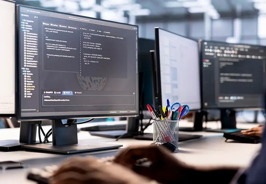 Developer writing and debugging code on multiple monitors in a modern software development workspace.