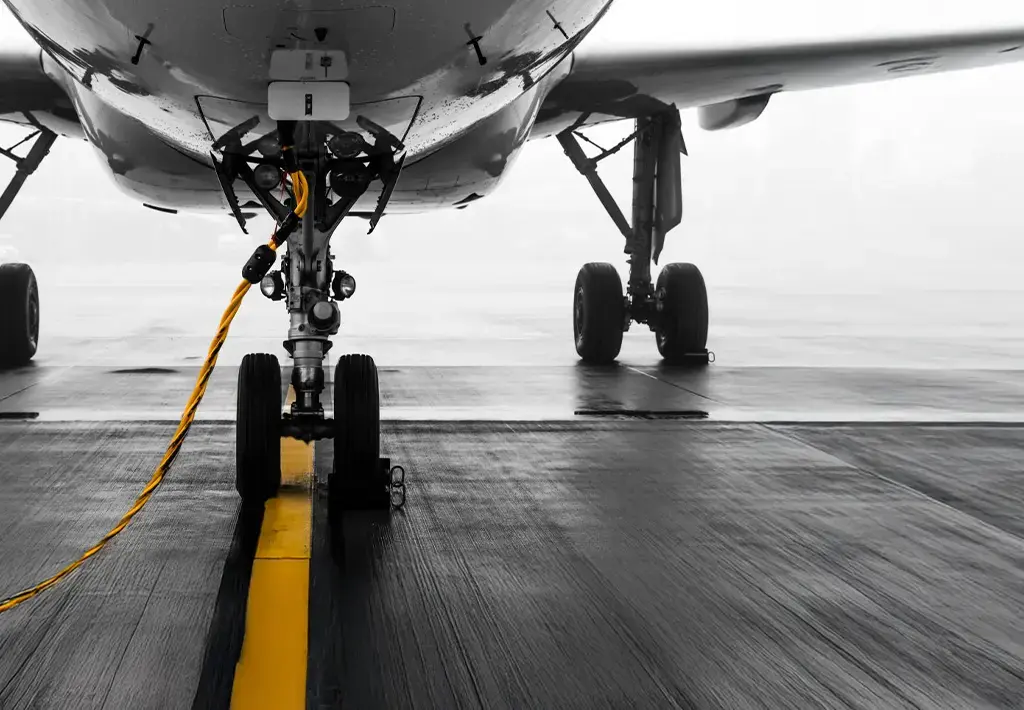 Close-up of airplane landing gear and tow cable on tarmac, representing travel logistics and aviation technology.