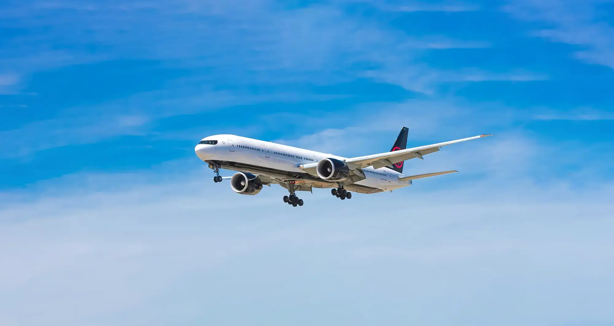 Commercial airplane in flight against blue sky, highlighting innovation in travel and aviation tech.