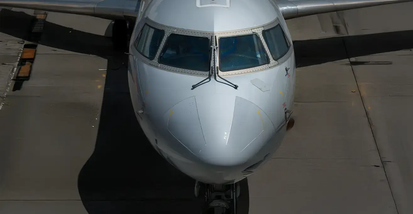 Front view of a commercial airplane on a taxiway, highlighting cockpit and fuselage design.