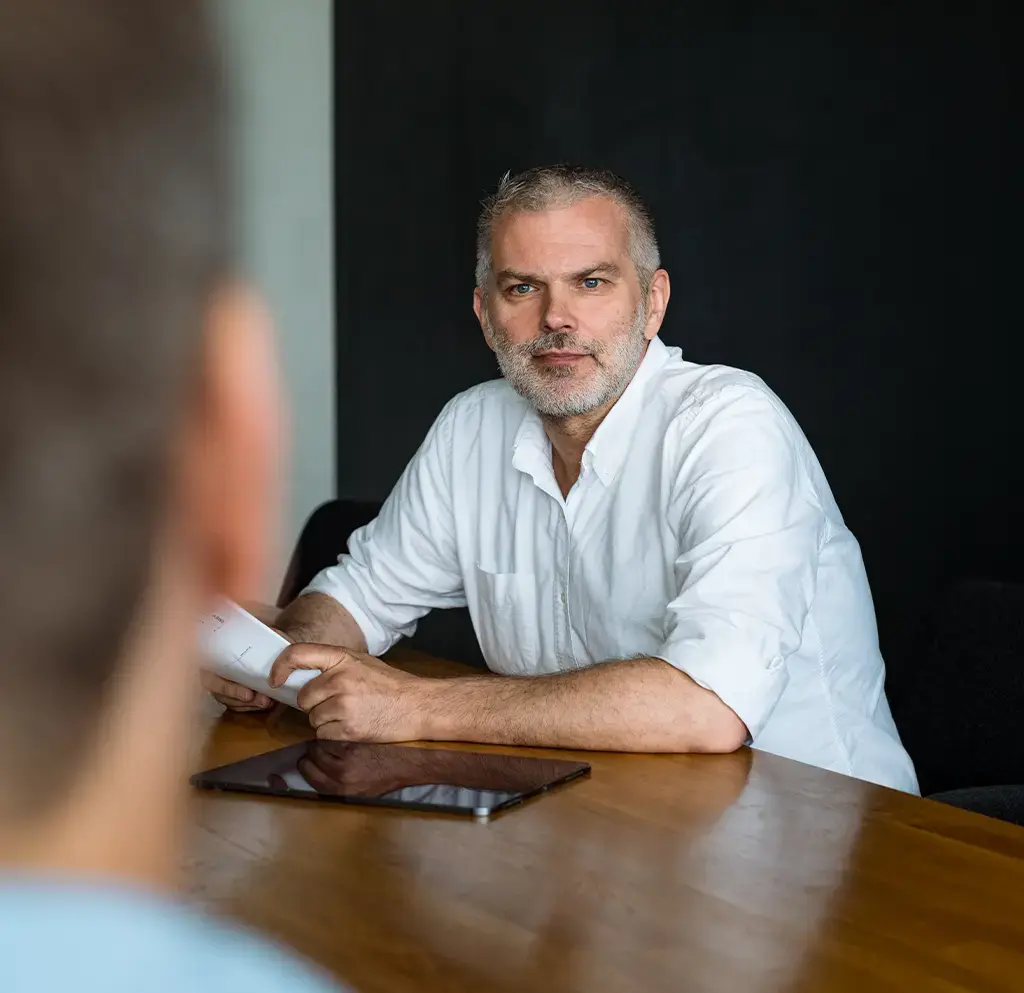 Professional in discussion at a conference table with tablet, representing leadership in digital strategy.