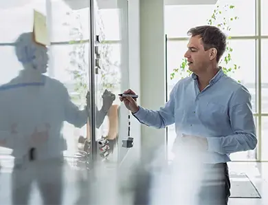 A professional writing on a whiteboard in a bright office space, brainstorming ideas for a project