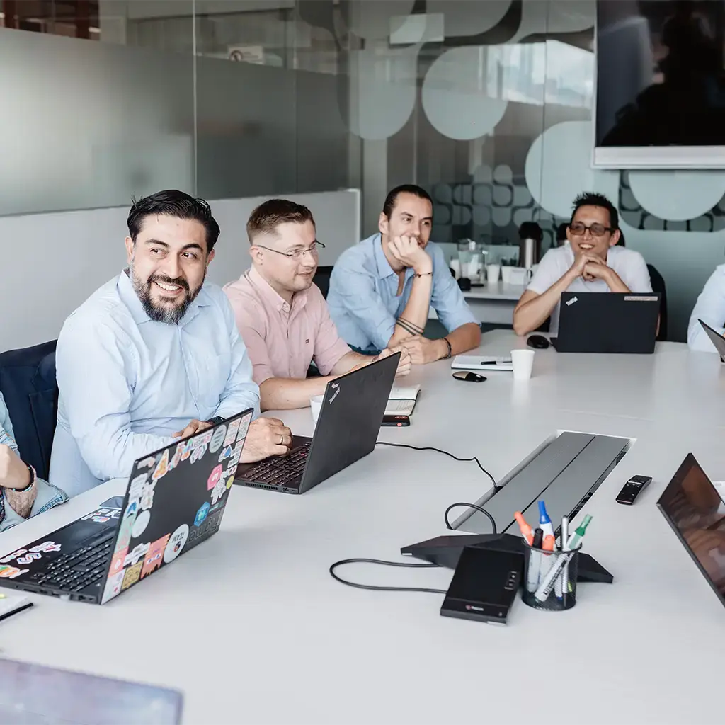 Team collaborating around a conference table with laptops during a strategy meeting.