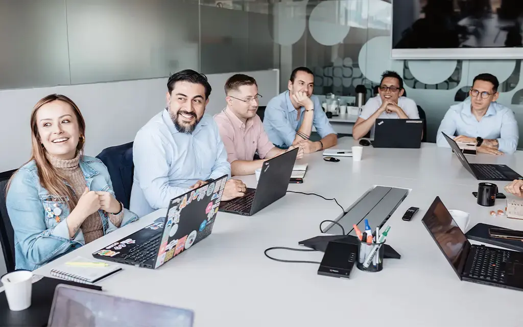 Team collaborating around a conference table with laptops during a strategy meeting.