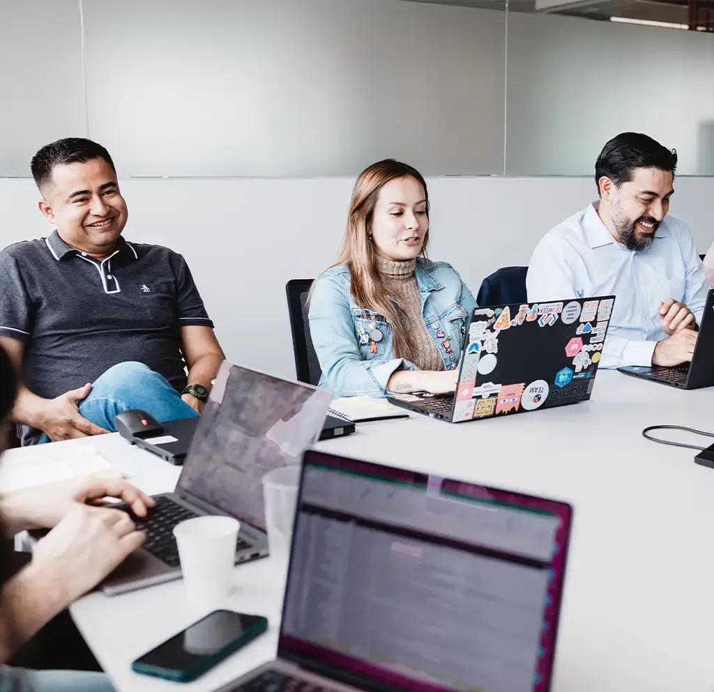 Team collaborating around a table with laptops during a software development meeting
