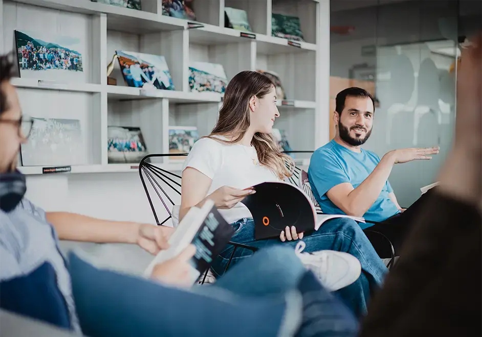 Team members engaged in a casual discussion while reviewing documents in a modern office lounge.
