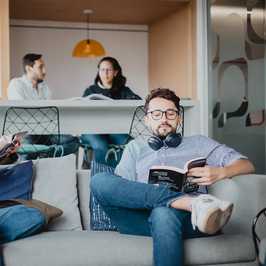 Team members relaxing and reading in a modern, collaborative office lounge.
