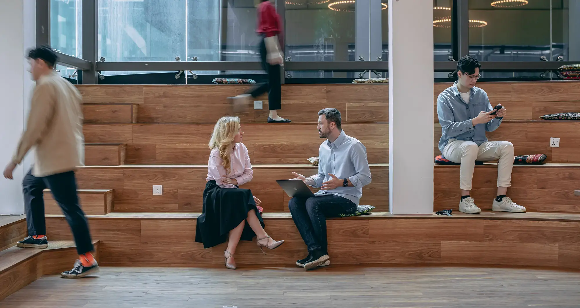 male and female endava coworkers having discussion while sitting on wood seating
