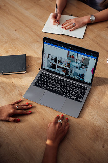 Team collaborates around a laptop showing a digital workspace for hybrid planning and innovation