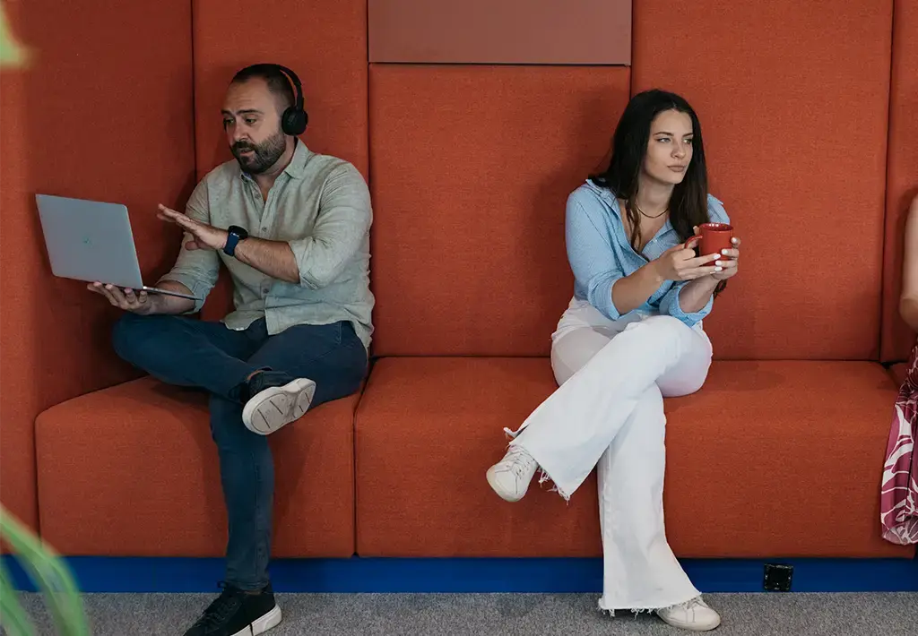 Team members in a modern lounge area using devices and collaborating, reflecting Endava’s digital workplace culture.