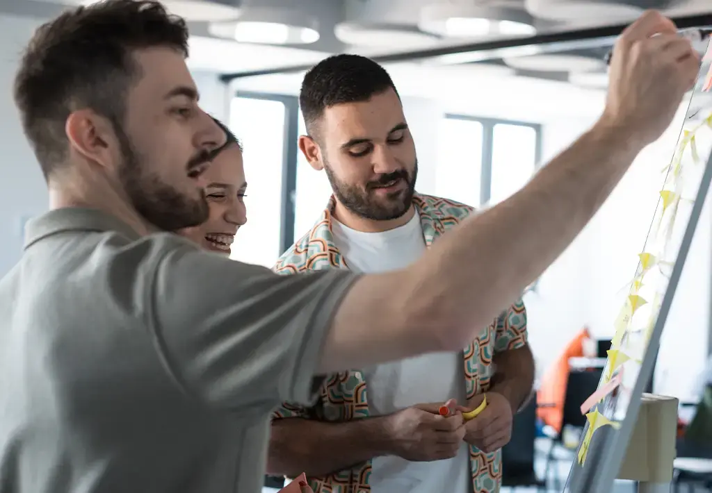 Team collaborating with sticky notes during a brainstorming session in a modern tech workspace.