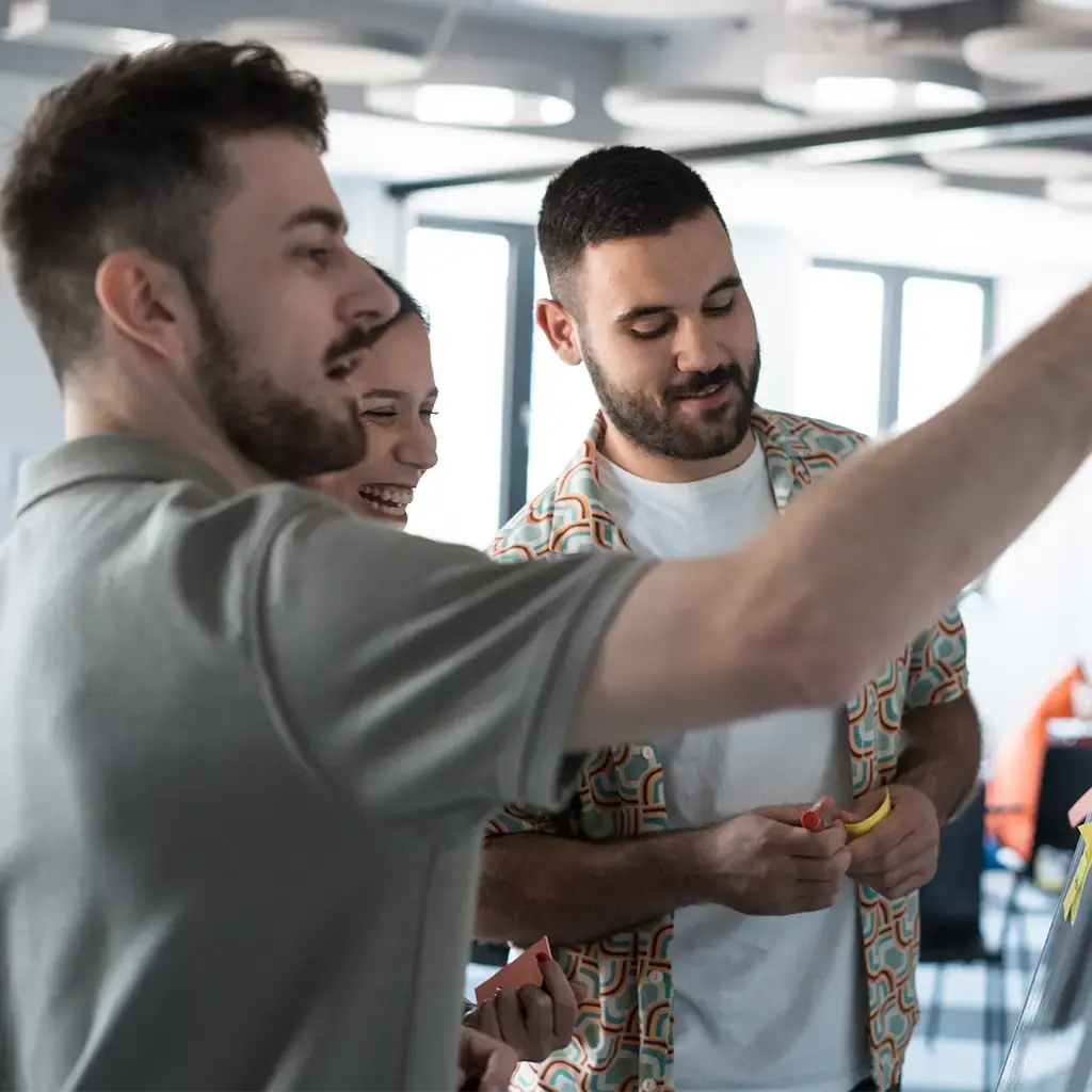 Team collaborating with sticky notes during a brainstorming session in a modern tech workspace.