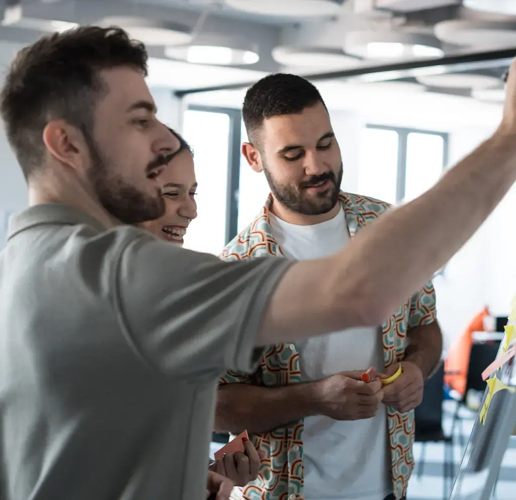 Team collaborating with sticky notes during a brainstorming session in a modern tech workspace.