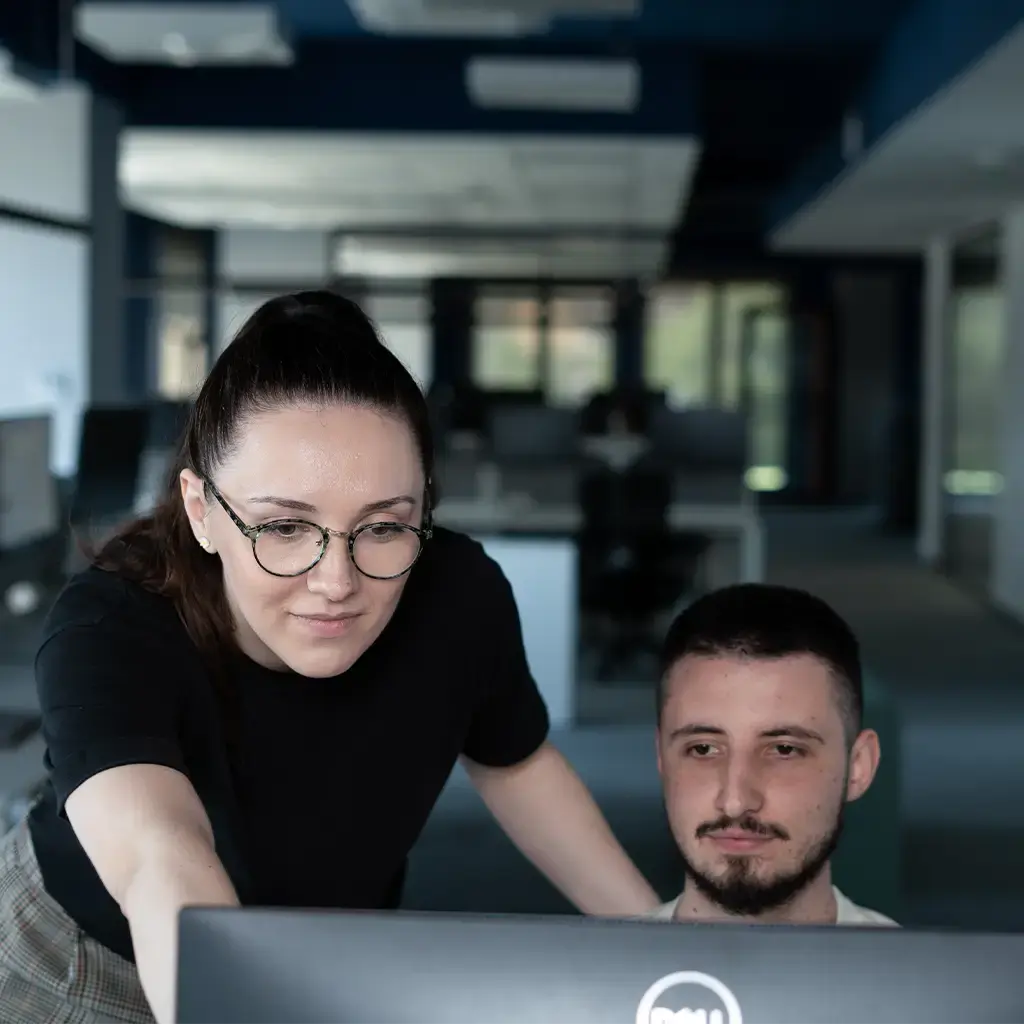 Two colleagues collaborating on a project at a computer in a modern office setting.