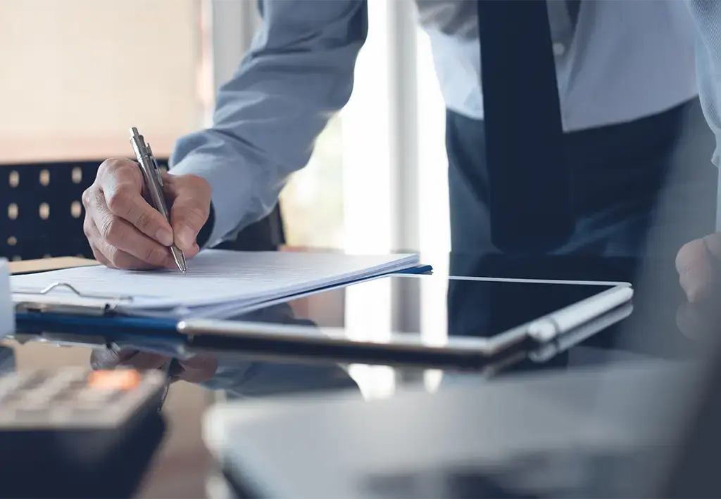 Business professional reviewing documents beside a tablet, symbolizing strategic planning and leadership.