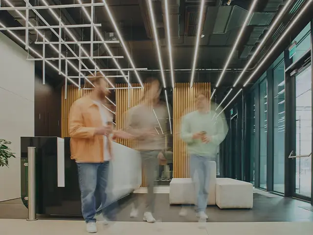 Modern office lobby with three people in motion, representing innovation and global collaboration.