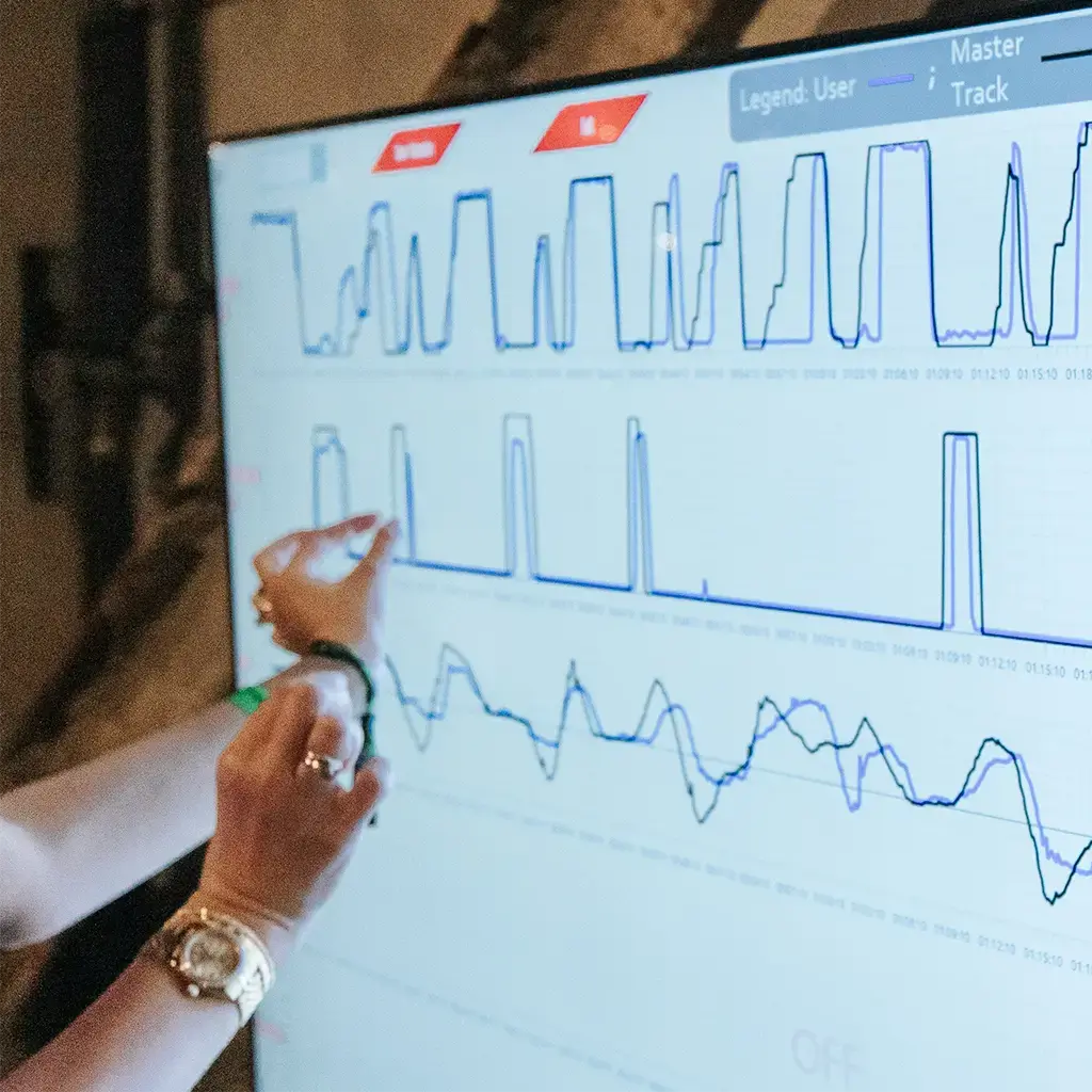 Person analyzing performance data visualized on a large digital screen with graphs and metrics.