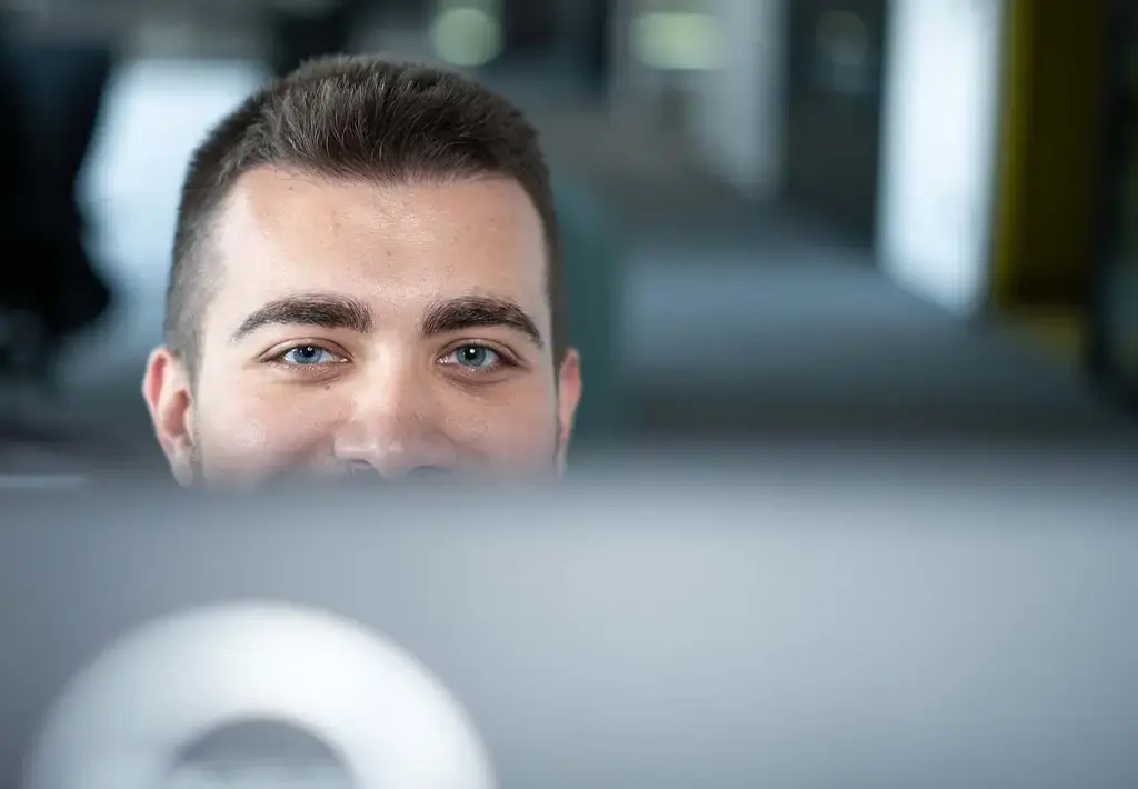 Team member focused on work behind a computer screen in a modern office setting.