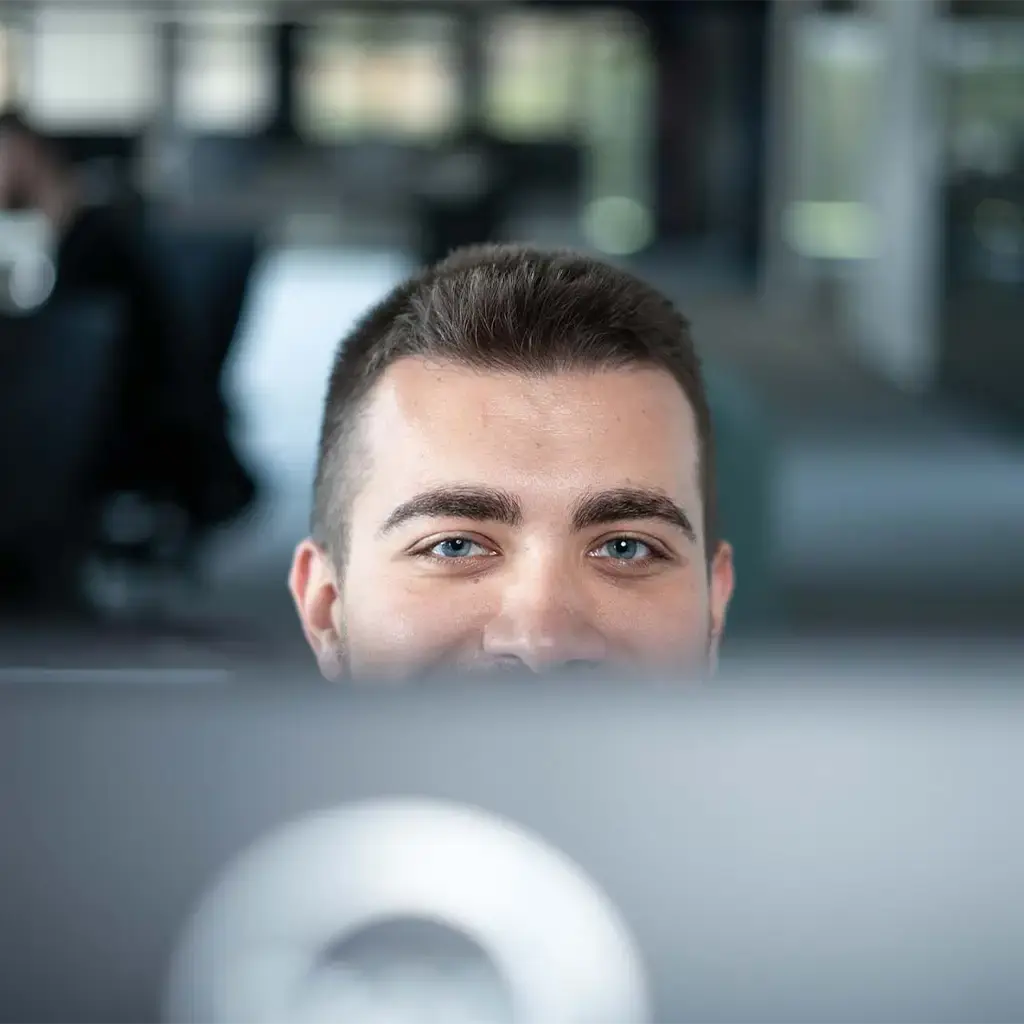 Team member focused on work behind a computer screen in a modern office setting.