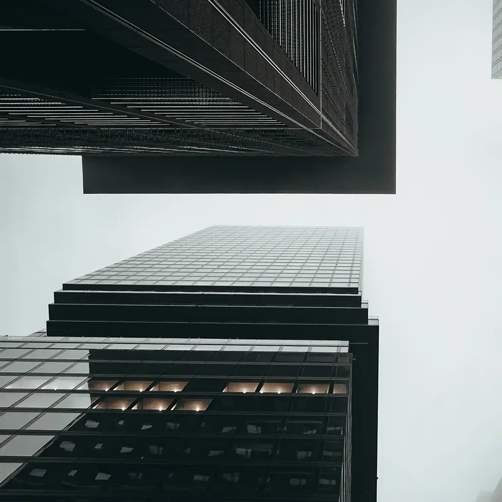 Modern skyscrapers viewed from below against a foggy sky, symbolizing growth and digital ambition.
