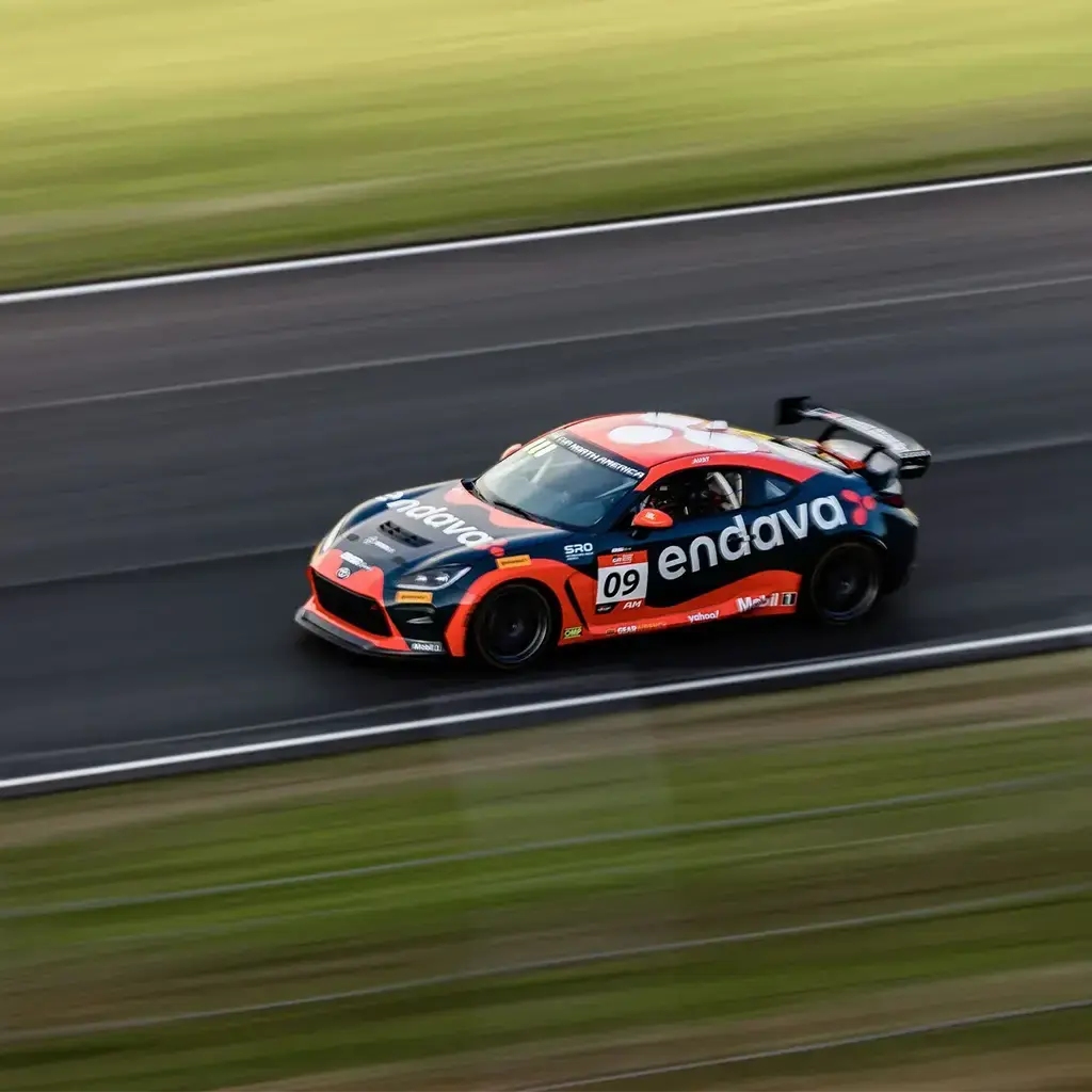 Endava-branded race car speeding on a track during a motorsport event.